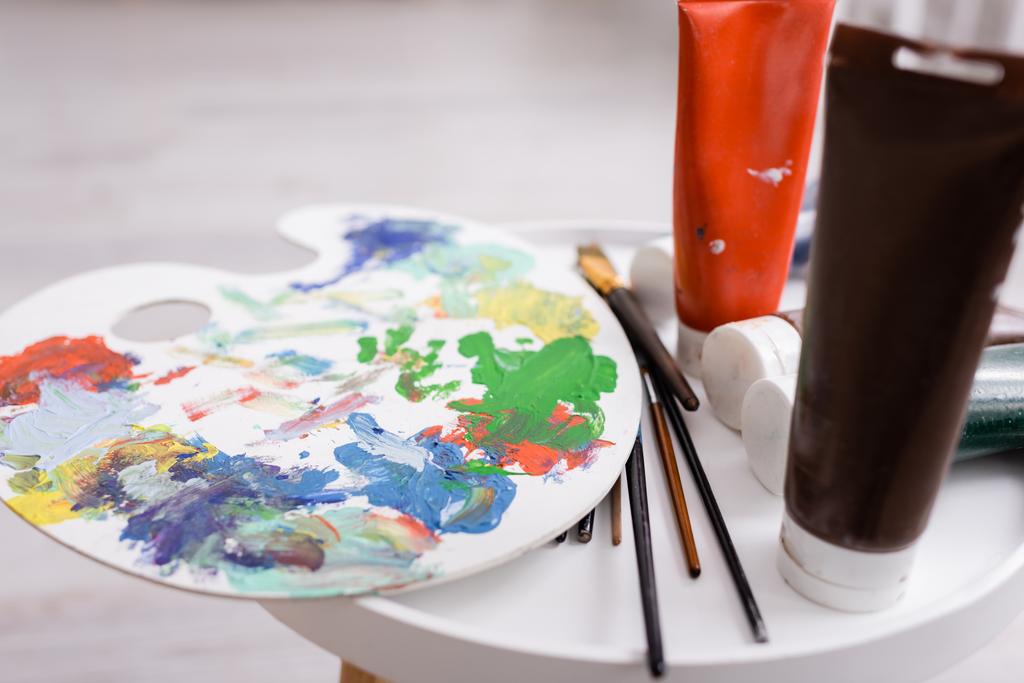 コーヒーテーブルの上の塗料でチューブの近くの絵筆やパレット - 写真・画像