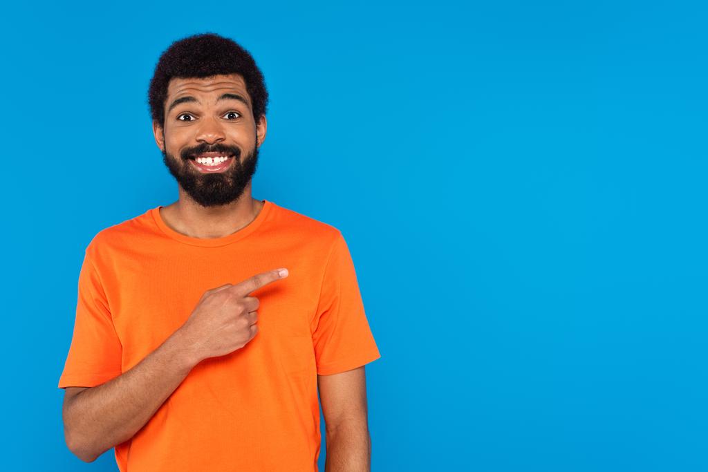 sorridente afro-americano apontando com o dedo isolado em azul - Foto, Imagem