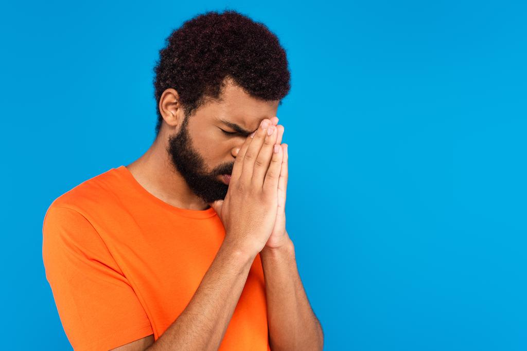 homme afro-américain barbu priant isolé sur bleu - Photo, image