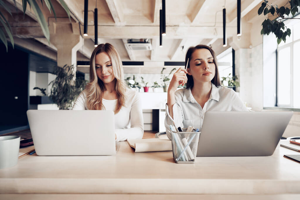 Дві молоді жінки обговорюють бізнес-проект разом в офісі
 - Фото, зображення