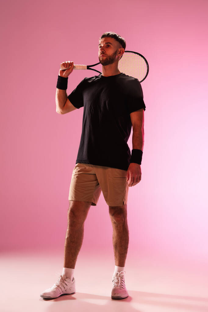 Giovane uomo caucasico che gioca a tennis isolato su sfondo rosa studio, azione e movimento concetto - Foto, immagini