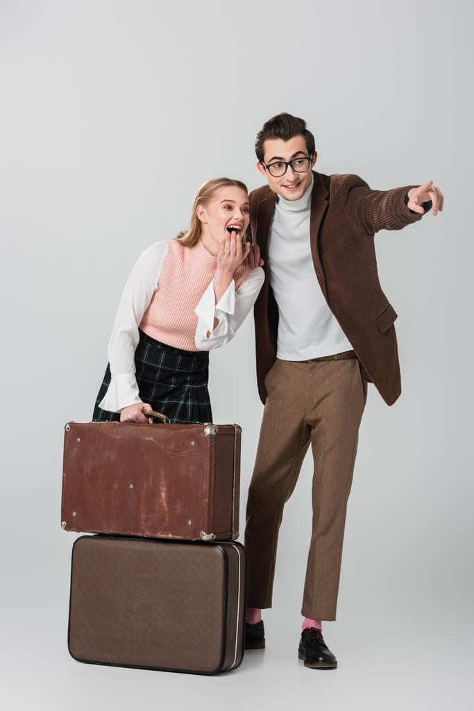 excited woman near suitcases and man pointing with finger on grey background - Photo, Image
