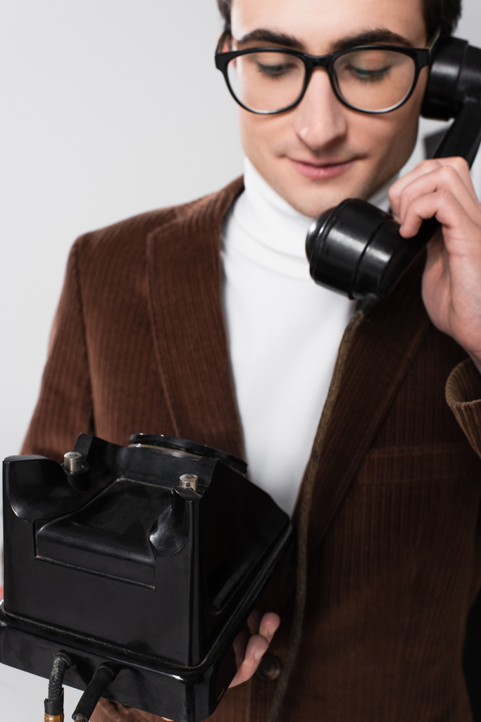 staromódní muž v hnědém blejzru mluví na retro telefon izolované na šedé - Fotografie, Obrázek