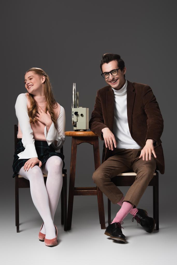 Lachendes Paar schaut Komödie auf Kinoprojektor auf grauem Hintergrund - Foto, Bild