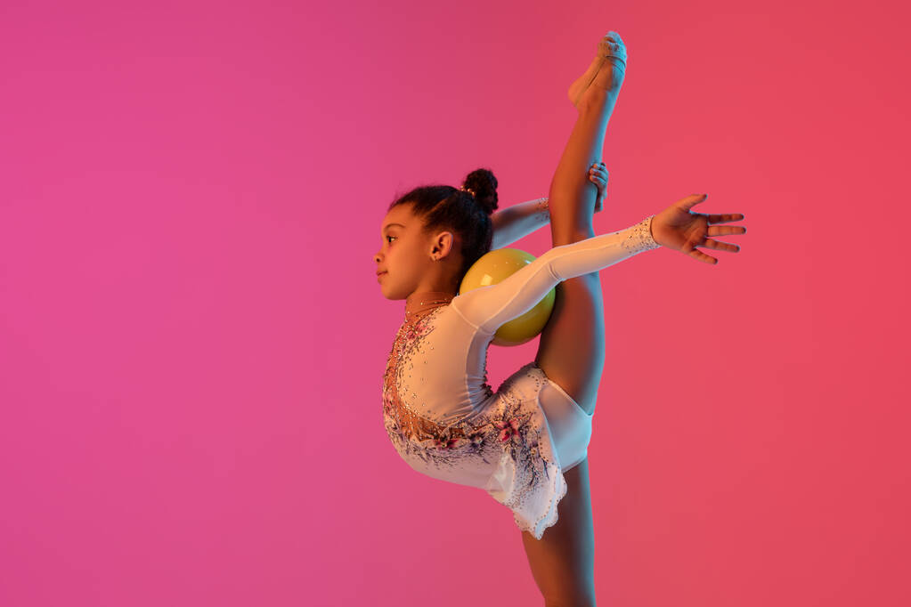 Afroamerykańska gimnastyczka rytmiczna, ładna dziewczyna ćwicząca na tle gradientowego studia w neonowym świetle - Zdjęcie, obraz