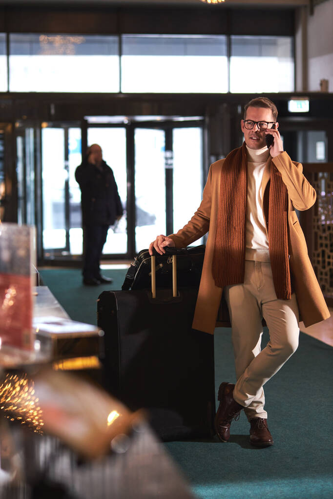 Впевнений чоловік у модному пальто йде на прийом, приймаючи багаж
 - Фото, зображення