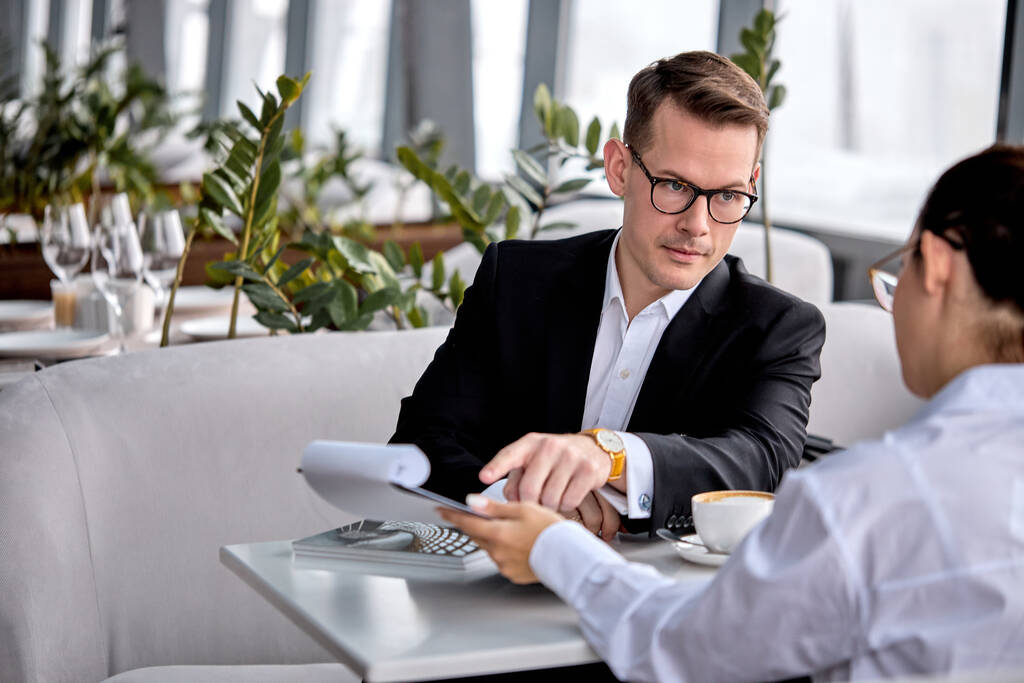 Jóképű fickó szemüvegben leül beszélgetni a kollégájával, üzleti ügyekről beszélgetni. - Fotó, kép