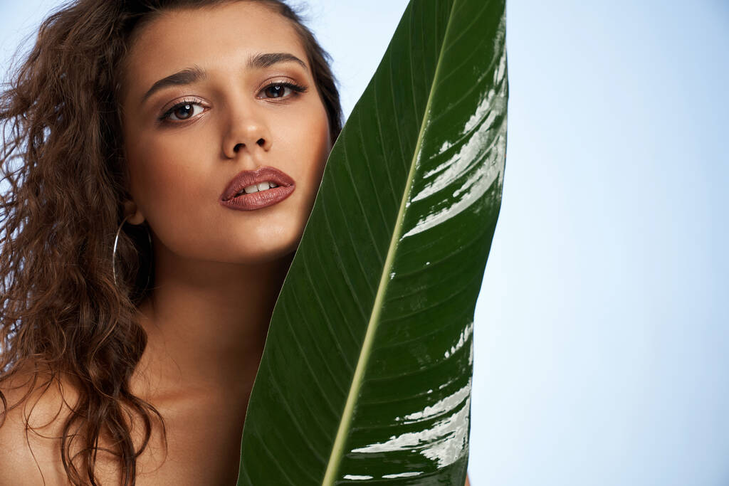  Beautiful model with curly hair with big green leaf.  - Photo, Image