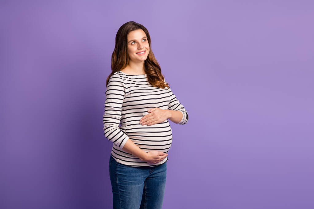 Фотопортрет беременной мечтательной женщины, изолированный на ярком фиолетовом фоне - Фото, изображение