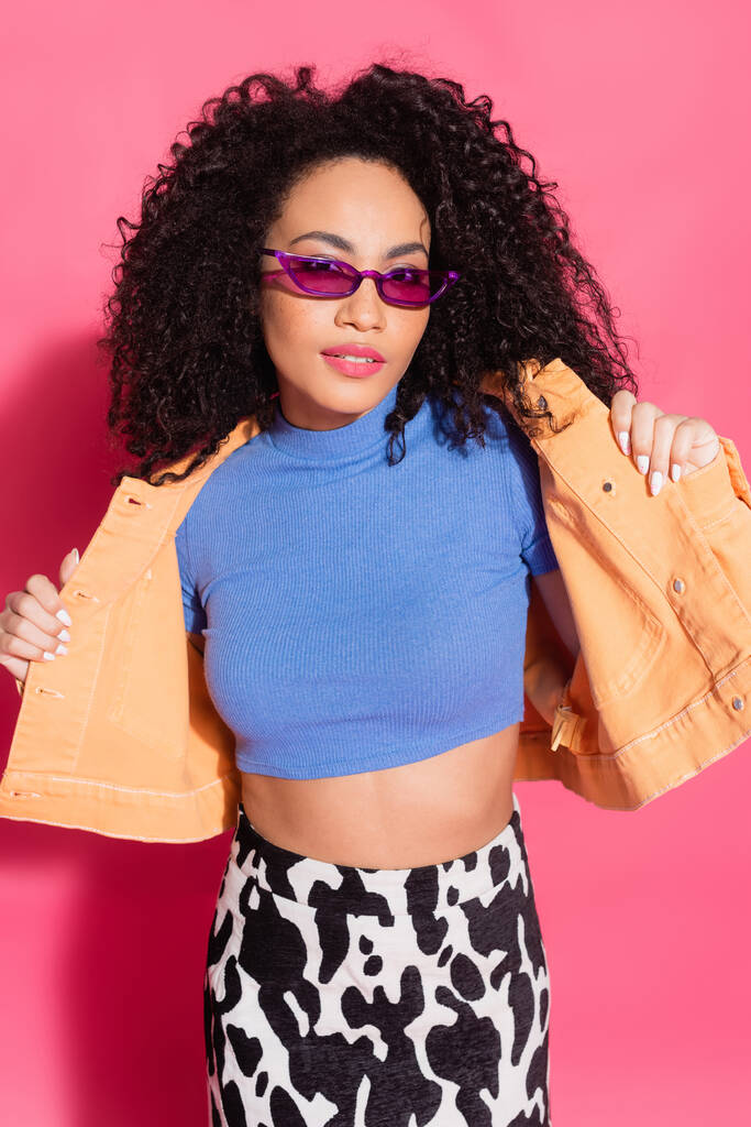 mujer afroamericana de moda en gafas de sol posando en rosa  - Foto, Imagen