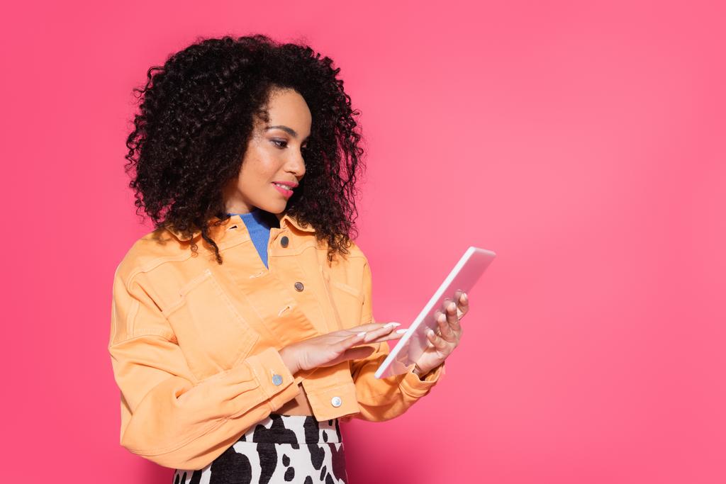 ricci donna afroamericana utilizzando tablet digitale isolato su rosa  - Foto, immagini