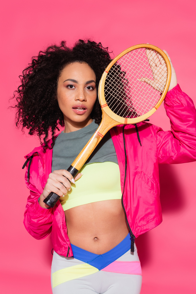 sporty brunette african american woman holding tennis racket on pink - Photo, Image