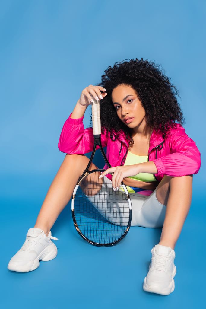 african american woman holding tennis racket while sitting on blue - Photo, Image