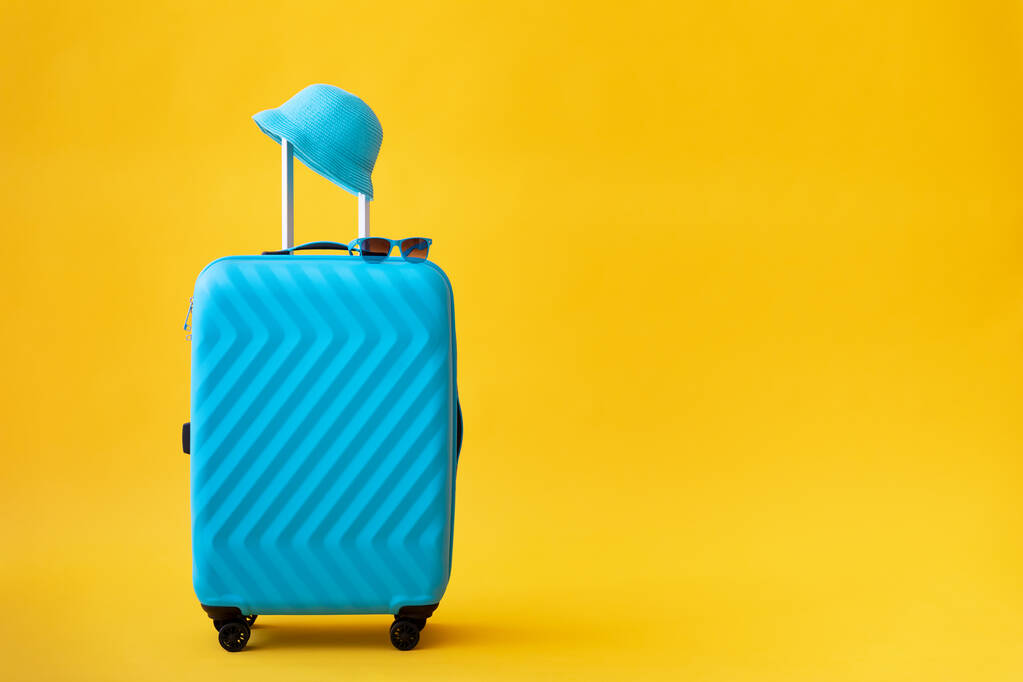 Niebieska walizka na żółtym tle. Koncepcja wakacji letnich i podróży - Zdjęcie, obraz