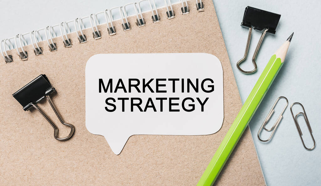 Szöveg marketing stratégia egy fehér matrica irodai papír háttér. Az üzleti, pénzügyi és fejlesztési koncepció lapos fektetése - Fotó, kép