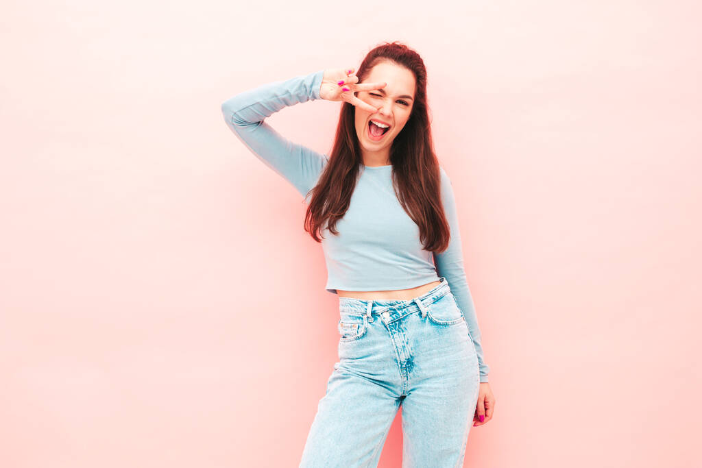 Portret van jonge mooie glimlachende vrouw in hippe zomerkleding. Sexy zorgeloze vrouw poseren in de buurt van roze muur in de studio. Positief model heeft plezier binnen. Vrolijk en gelukkig - Foto, afbeelding