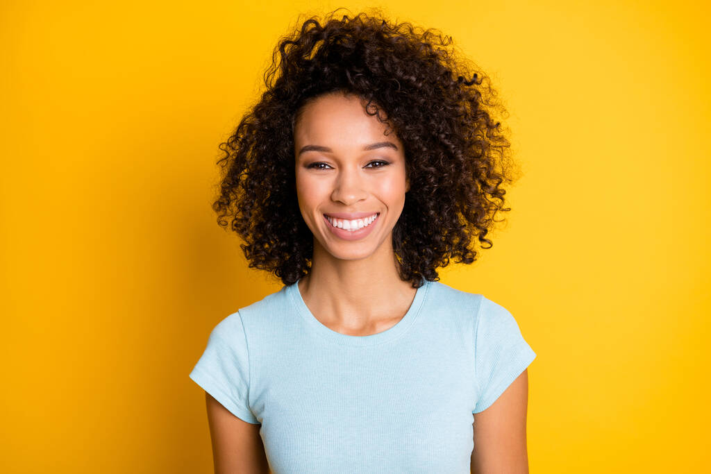 Foto retrato de la hermosa chica rizada afro-americana sonriendo aislada sobre fondo de color amarillo vivo - Foto, imagen