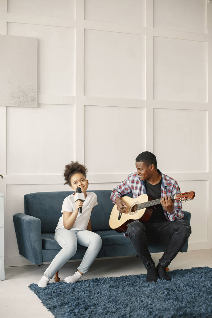 Papai está sentado com uma guitarra e filha com um microfone - Foto, Imagem