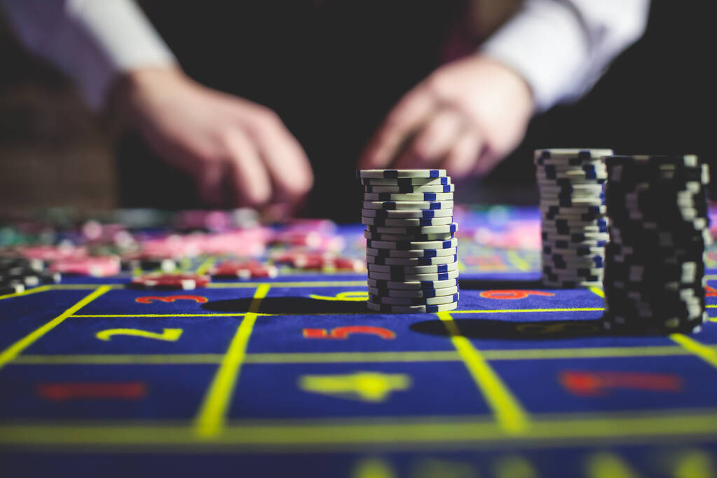 Lähikuva elinvoimainen kuva monivärinen kasino pöytä ruletti liikkeessä, jossa pelimerkkejä. käsi krupieeri, rahaa ja ryhmä uhkapeli rikkaita rikkaita ihmisiä pelaa taustalla  - Valokuva, kuva