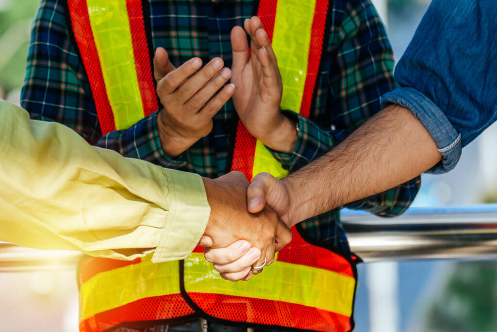Partnerstwo. zespół pracowników budowlanych ściskający dłoń z klientem po zakończeniu spotkania biznesowego w celu powitania umowy o rozpoczęcie projektu na placu budowy, koncepcji biznesowej i wykonawczej - Zdjęcie, obraz