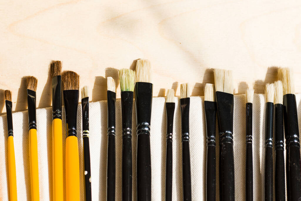 A closeup of a set of different paintbrushes on the table under the lights - Photo, Image