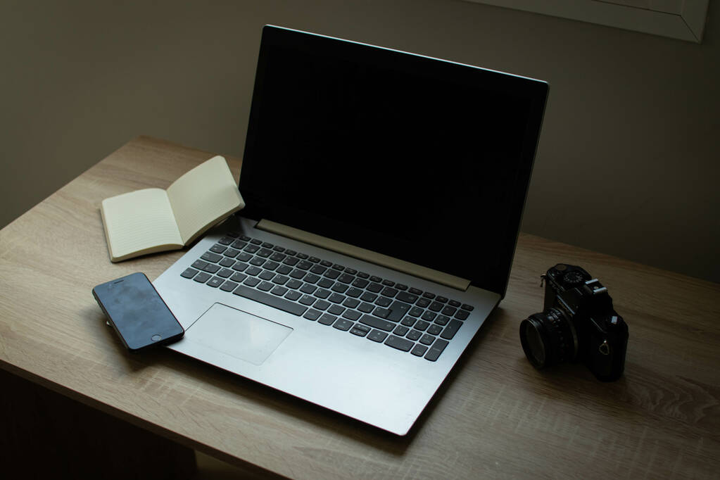 Un portatile, un quaderno aperto e un cellulare sul tavolo di un ufficio. - Foto, immagini