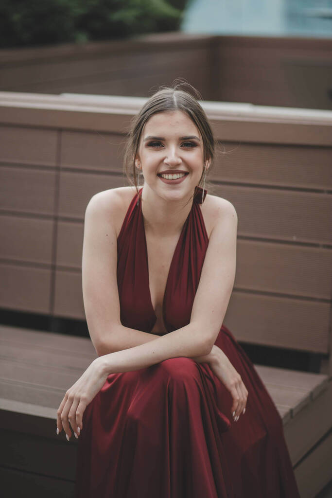 Uma bela mulher caucasiana sexy em um vestido sem costas vermelho sentado em um café ao ar livre - Foto, Imagem