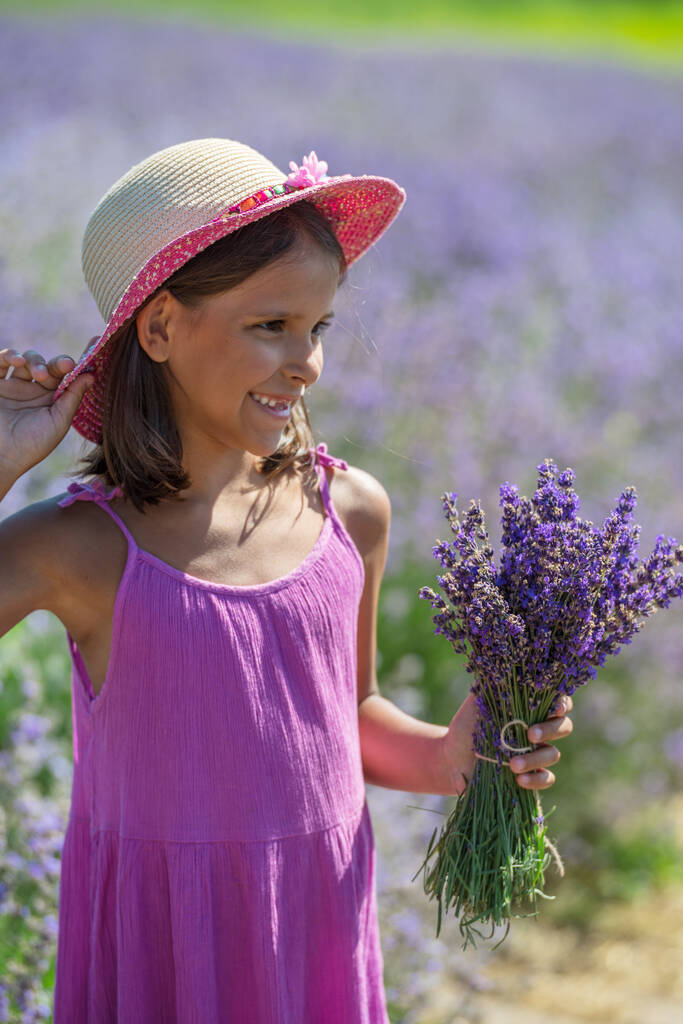 Portrét malé holčičky s levandulovou kyticí v ruce na levandulovém poli. - Fotografie, Obrázek