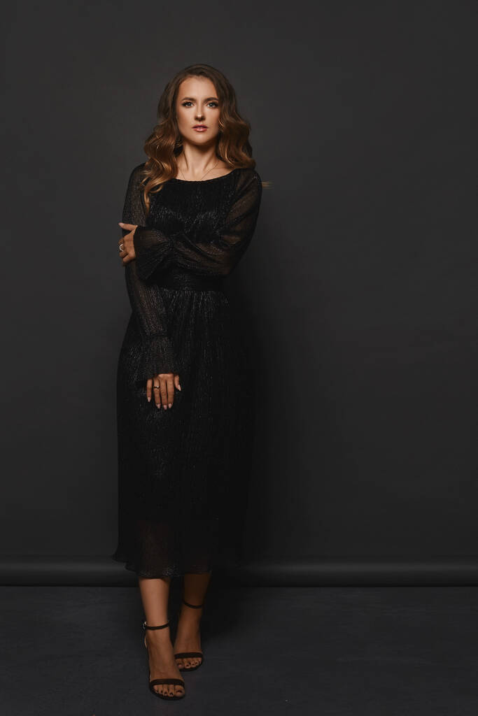 Модель жінки в чорній вечірній сукні позує на чорному тлі
 - Фото, зображення