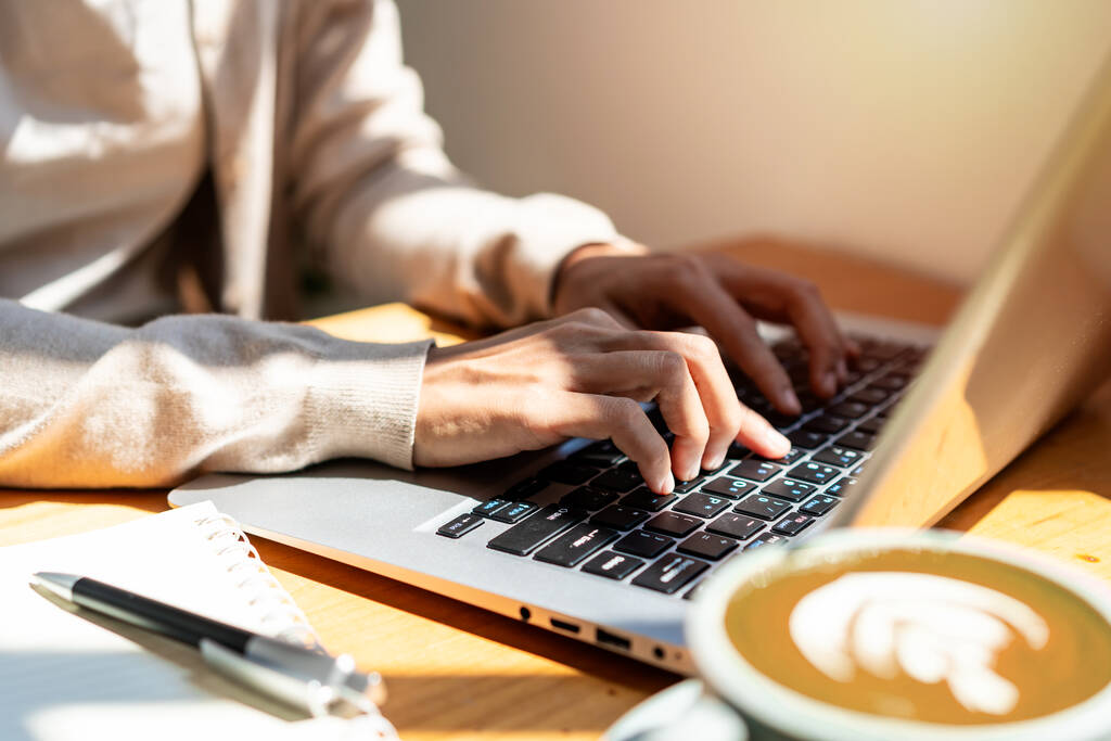 Jonge vrouw met kopje koffie zitten en werken op laptop in de coffeeshop - Foto, afbeelding