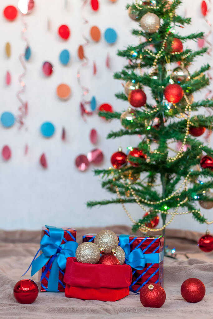 Festliches Weihnachtsspielzeug in einem roten Sack liegt unter dem Baum. Weihnachten und Neujahr. Das Konzept eines Werbebanners.  - Foto, Bild