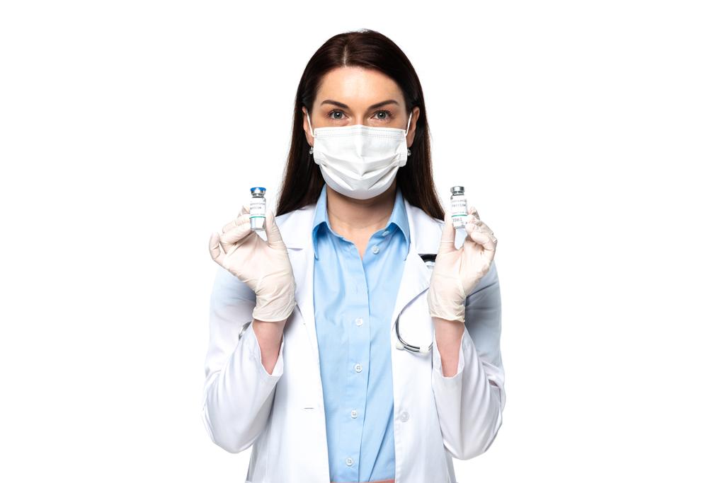 Medico in maschera medica che tiene vasetti con vaccino isolato su bianco  - Foto, immagini