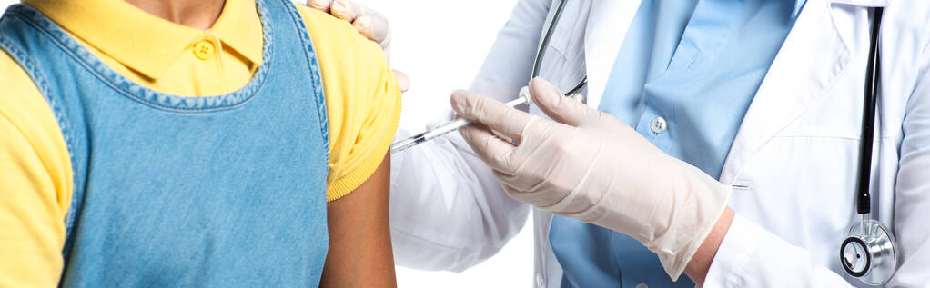 Обрезанный взгляд врача, делающего вакцинацию африканского американского ребенка, изолированного на белом, баннер  - Фото, изображение