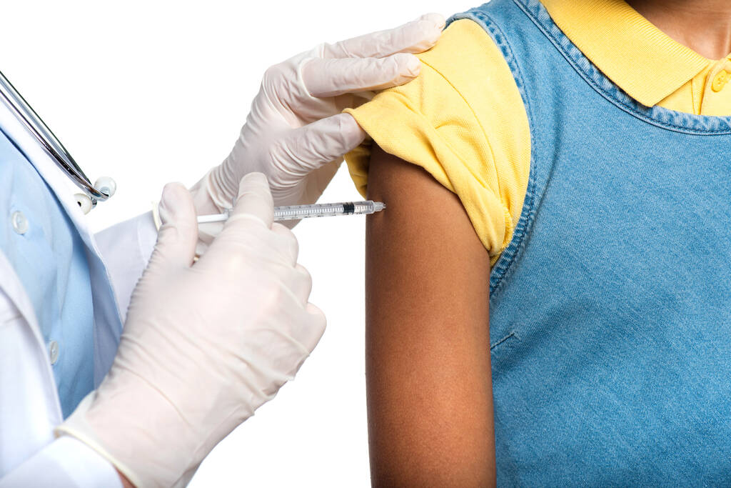 Обрезанный взгляд врача в латексных перчатках, делающего прививку африканского американского ребенка, изолированного на белом  - Фото, изображение