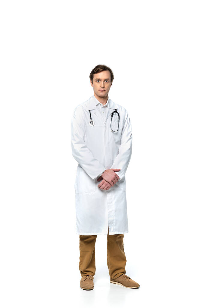 Orvos fehér kabátban nézi kamera fehér háttér  - Fotó, kép