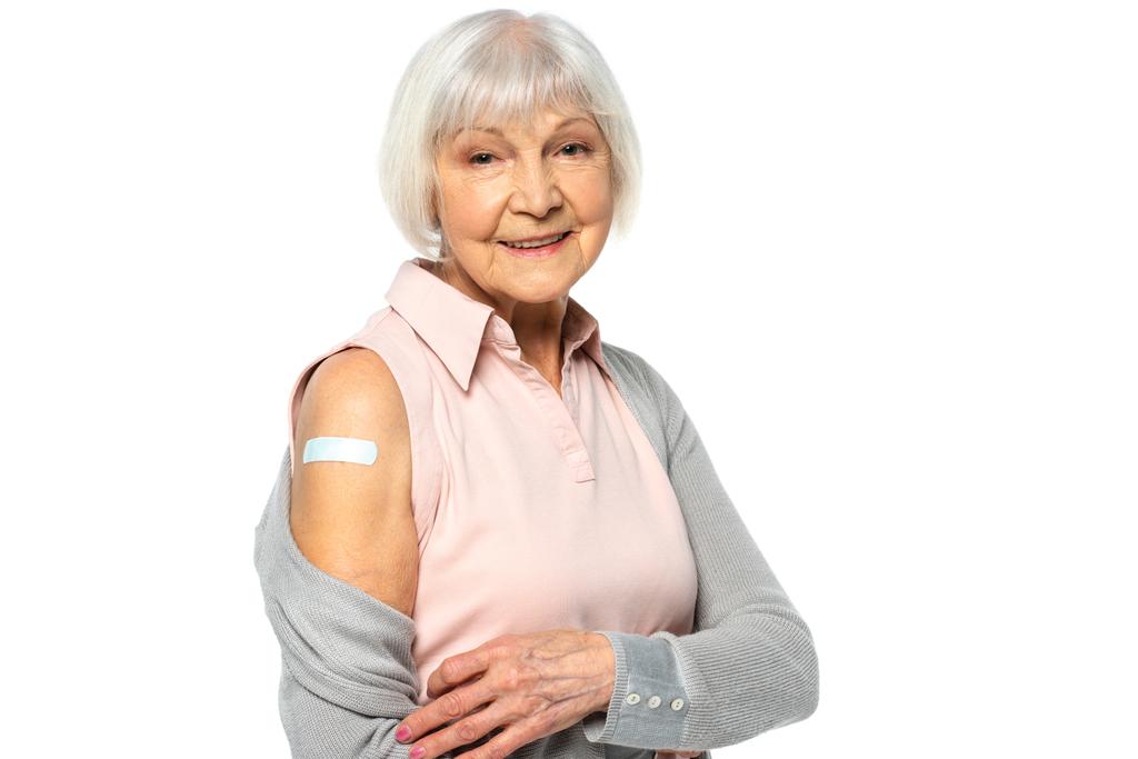 Mujer mayor sonriente con parche adhesivo en brazo aislado en blanco  - Foto, Imagen