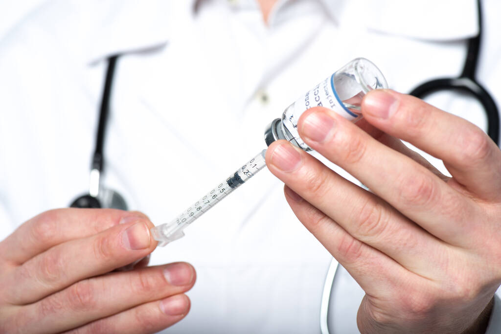 Gewassen zicht op wazig arts oppikken vaccin in spuit geïsoleerd op wit  - Foto, afbeelding