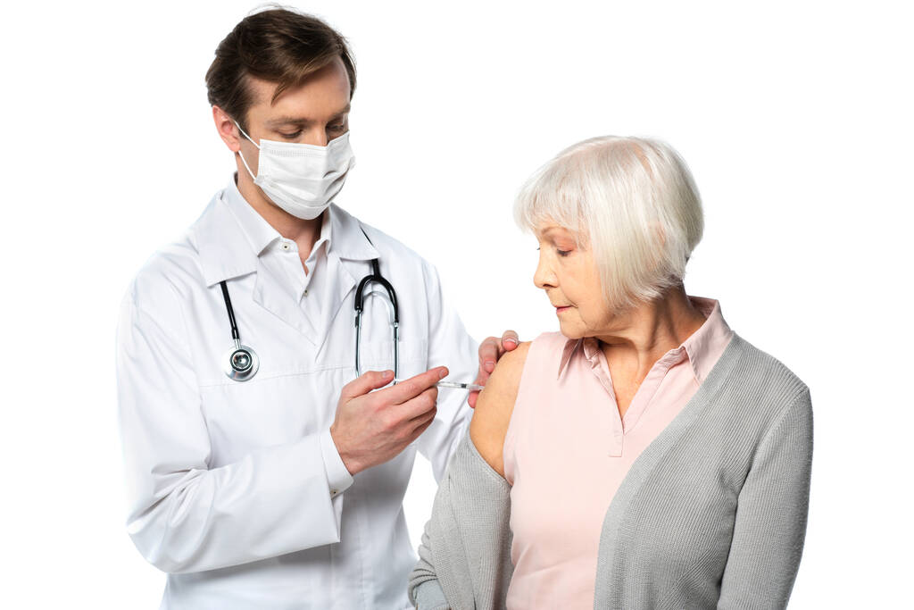 Médico en máscara médica haciendo la vacunación de la patente senior aislado en blanco  - Foto, imagen