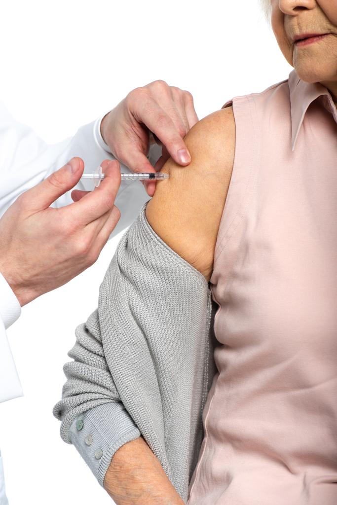 Ausgeschnittene Ansicht des Arztes mit Spritze tun Impfstoffinjektion von Seniorin isoliert auf weiß  - Foto, Bild
