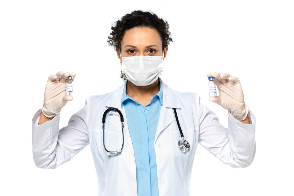 白い上に隔離されたワクチンを保持する医療マスクのアフリカ系アメリカ人医師  - 写真・画像