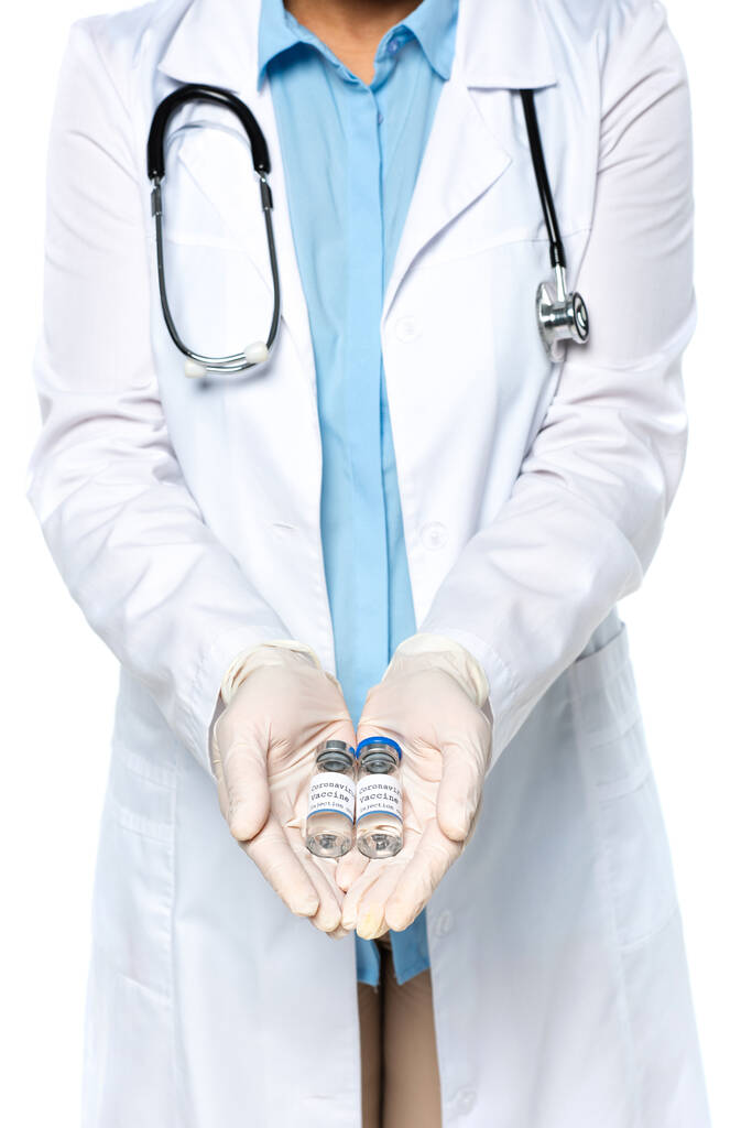 白い上に隔離されたワクチンで瓶を保持ラテックス手袋で医師の作物ビュー  - 写真・画像