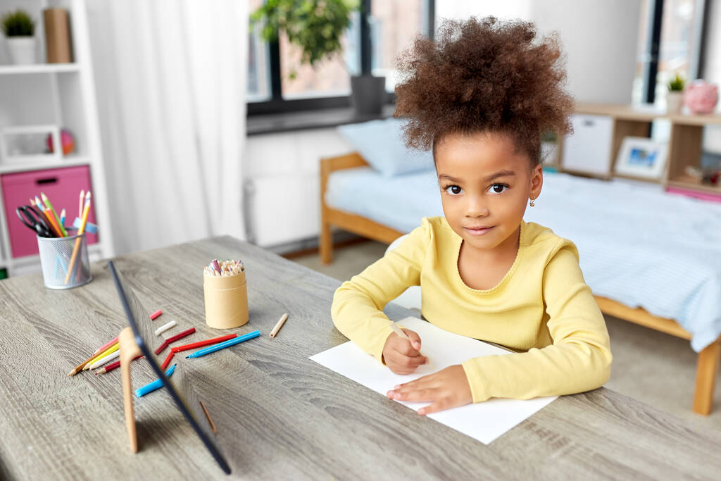 маленькая девочка рисует с цветными карандашами дома - Фото, изображение