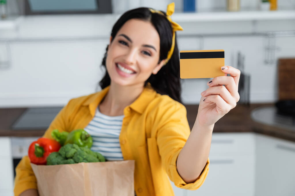 食料品やクレジットカードで紙袋を持っている幸せとぼやけた女性 - 写真・画像
