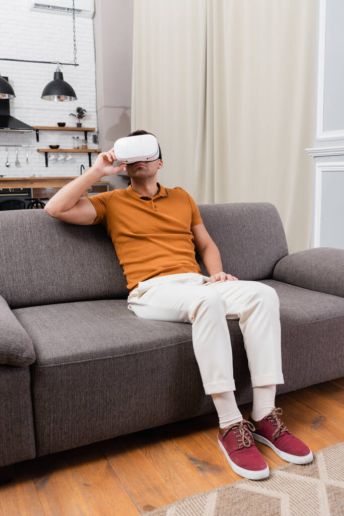 Mann justiert vr Headset beim Spielen auf der Couch zu Hause - Foto, Bild