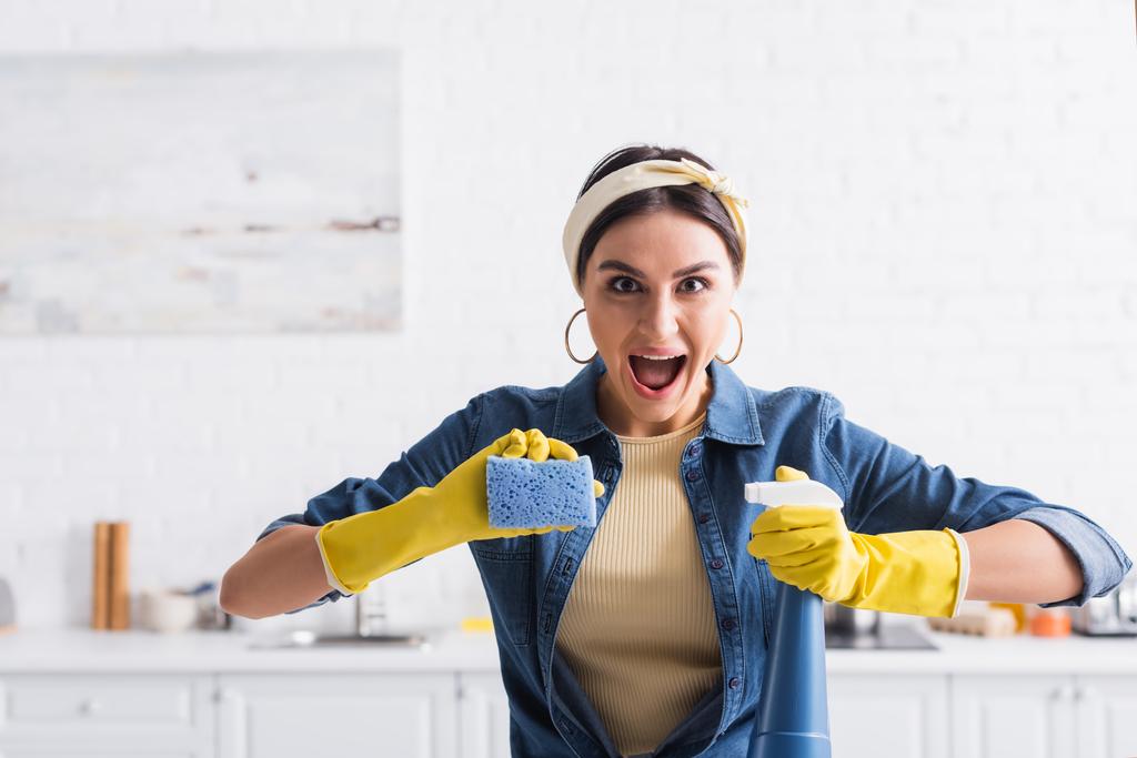 dona de casa animado com detergente spray e esponja na cozinha  - Foto, Imagem