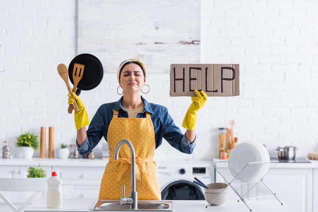 Грустная домохозяйка с плакатом с помощью надписи и посуды возле раковины   - Фото, изображение