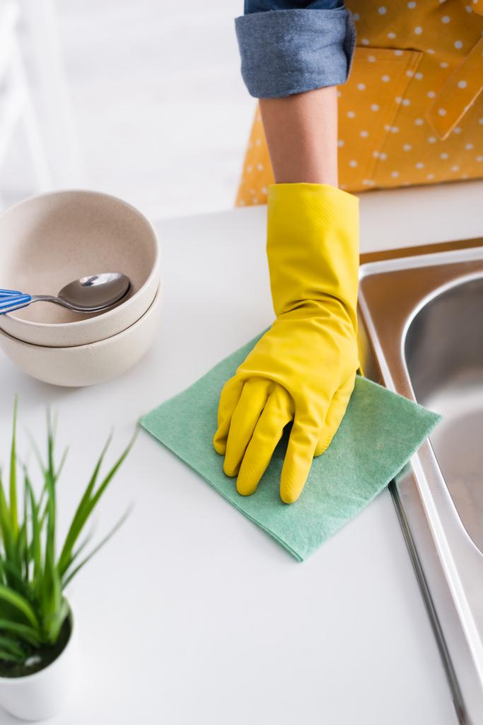 Rajatut näkymä nainen puhdistaa keittiö työtaso lähellä levyt ja pesuallas  - Valokuva, kuva
