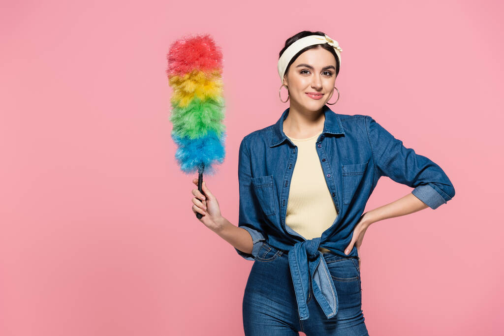 Smiling woman in denim shirt holding dust brush isolated on pink - Photo, Image