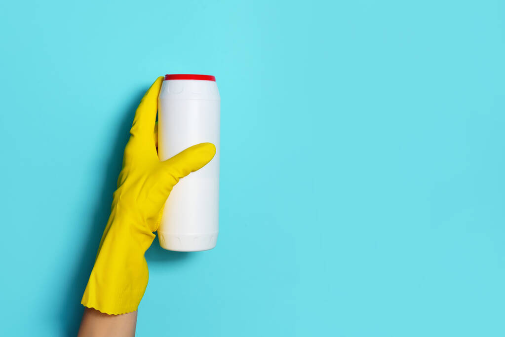 Hand in hand handschoen met witte plastic fles schoonmaakmiddel, huishoudelijke chemicaliën. Begrepen, ruimte. Schoonmaakservice concept. Chemische reinigingsmiddelen, borstels en benodigdheden voor huishoudelijk gebruik. Fles met wasmiddel - Foto, afbeelding