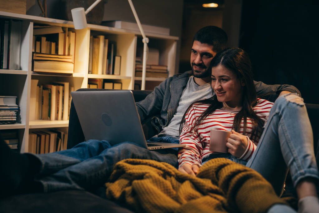ζευγάρι απολαμβάνει το χρόνο μαζί στο σπίτι, χρησιμοποιώντας το laptop - Φωτογραφία, εικόνα